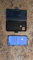Front of Pixel 5 powered on next to open blue folio case
