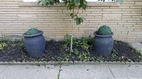Both blue patina urn planters in garden bed