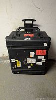 Front view of black Pelican 1690 case with wheels and stickers