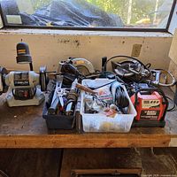Lot overview showing bench grinder, saws, charger, hand tools, hardware