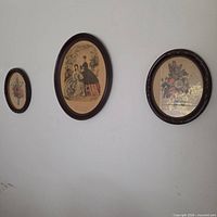 Three oval framed prints on wall showing relative sizes and subjects