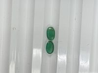 Front view of two oval emeralds on white background