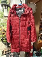 Front view of red Calvin Klein quilted coat hanging