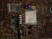 Group shot showing both spectacles, bracelet, chess pieces in mesh bag, prayer tiles, and paper program