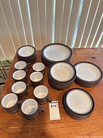 Full set of plates, bowls, mugs and saucers laid out on table