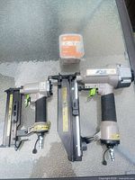 Two Blue Hawk pneumatic finish nailers with nails box on glass table, top view
