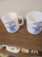 Both milk glass mugs on shelf showing overall appearance