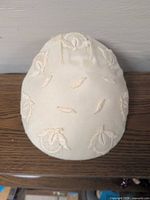 Top view of ivory pillbox hat showing overall shape and appliqué placement