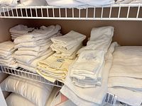 Stacked white towels on shelving, various sizes