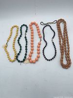 Group shot of five beaded necklaces in various colours displayed flat