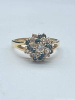 Ring front view showing cluster of clear and dark green stones and gold-plated setting