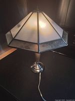 Full lamp illuminated showing octagonal stained glass shade and brushed nickel base