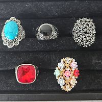 Five assorted fashion rings displayed in jewelry tray
