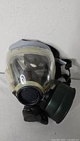 Front view of gas mask showing visor, filter and straps