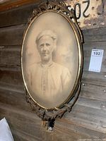 Full view of metal oval frame with sepia portrait, wall mounted