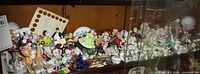 Shelf view showing large grouping of miniature figures, tea sets, thimbles and other small collectibles