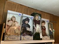 Five boxed porcelain dolls on shelf