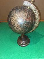 Front left view of terrestrial globe on wood base showing antiqued map graphics and metal meridian ring
