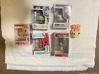 Six boxed figures and one loose figure head displayed on towel
