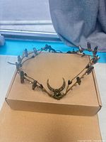 Front view of tiara on box showing crescent moon centerpiece and overall shape