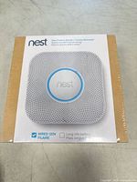 Front view of sealed Nest Protect retail box showing product image and wired 120V icon