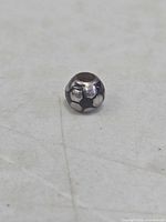 Soccer ball charm bead front view displaying black enamel panels and drill hole