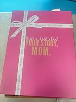 closed pink gift box with ribbon graphic and gold text