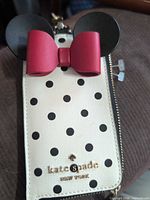 Front view of cardholder showing polka dot pattern, ears, bow, and brand logo