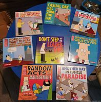 All eight Dilbert softcover books spread on table showing covers