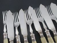 Close view of knife blades, chased detail, fork tines and ferrules