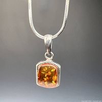 Close-up of amber pendant and bail on silver chain