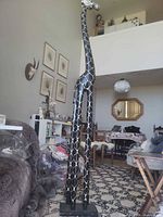 Full view of tall giraffe sculpture standing on base