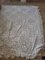 Full view of crocheted coverlet laid flat showing overall size and fringe