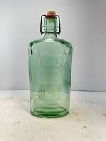 Front view showing entire bottle, embossed text, color, and general condition