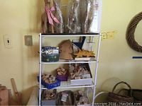 Full view of metal shelving unit containing wooden animal figures, spools, and craft supplies on four shelves.