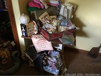 Kenmore sewing machine and several boxes of craft ribbons, lace, and knitted hats stacked on and around a table.