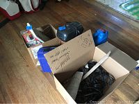 Cardboard boxes filled with soldering guns, hand grinders and other tool items along with some cases and a few labeled boxes.