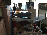 Wide shot of wooden whale decor piece on a shelf surrounded by vases and other glass decor items.
