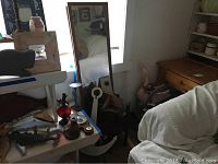 Room corner showing wooden anchor, mirror, iron goat door stopper and small side table among other items