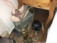 Photo showing the swan figurine, metal wheeling rack, vintage wine bottle, tin lantern, hole punch, and glass containers gathered on the floor near wooden furniture.