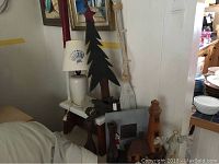 Overall view of items including wooden Christmas tree, white ceramic lamp, cast iron hooks, stool, lighthouse decor, and wooden framed mirror.