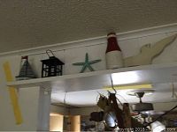 Shelf with various nautical-themed decorative items including seagull, oar, green starfish, white shells, and black lantern