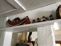 Top shelf in kitchen showing wooden watermelon slice and six wooden women figurines in aprons.