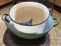 Three vintage enamelware pieces stacked: white stock pot, green roaster, gray candle holder inside stock pot.