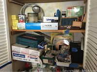 Full shelf with Moen faucet box, plumbers putty, shower head, pipe heating cable box, tools, and miscellaneous boxes and packages