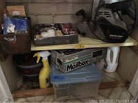 Overall view of items on wooden shelf showing Porter Cable sander, mailbox kit, hardware, plastic bin, and cleaning spray