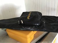 Black fabric carrying case with Robotoolz logo and yellow hard case beneath it