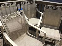 Four light-colored metal outdoor chairs with beige mesh seats grouped on a deck.
