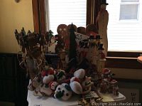 Photo showing a mix of the Christmas décor items including snowmen, gingerbread men, trees, and bears arranged on a table in front of a window.