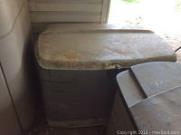 Side view of beige Rubbermaid deck box with visible dirt and placed outdoors.
